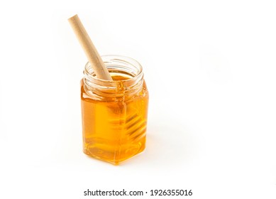 Glass jar of honey and dipper on a white background with space for text 