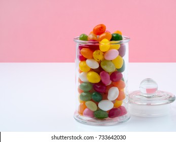 Glass Jar With Lid Filled With Colorful Candies On Bright Pink Background, Many Jelly Bean