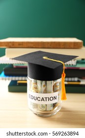 Glass Jar With Money For Education On Wooden Table Against Green Background