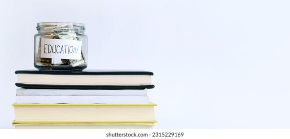 Glass jar with money on a stack of books. Piggy bank with dollars for education. Save money for future studies. Copy space - Shutterstock ID 2315229169