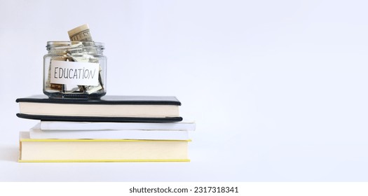 Glass jar with money on a stack of books. Piggy bank with dollars for education. Save money for future studies. Copy space - Shutterstock ID 2317318341