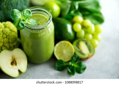 Glass jar mugs with green health smoothie, kale leaves, lime, apple, kiwi, grapes, banana, avocado, lettuce. Copy space. Raw, vegan, vegetarian, alkaline food concept. Banner - Powered by Shutterstock