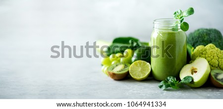Glass jar mugs with green health smoothie, kale leaves, lime, apple, kiwi, grapes, banana, avocado, lettuce. Copy space. Raw, vegan, vegetarian, alkaline food concept. Banner.