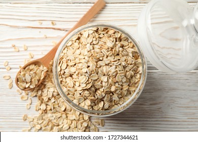 Glass jar with oatmeal and spoon on wooden background, top view