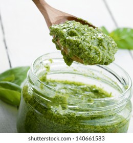 Glass Jar Of Pesto Sauce With Wooden Spoon