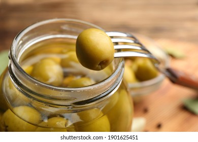 Glass jar of pickled olives and fork, closeup - Powered by Shutterstock