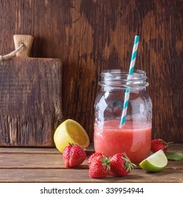 Glass Jar With Red Strawberry Smoothie, Served With Fresh Strawberries, Lemon And Lime Over Wooden Table. Square Image