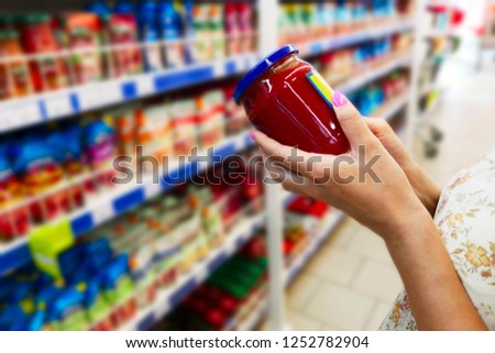 Glass jar of sauce in the hands of the buyer. Sauce in the hands of the buyer at the grocery store