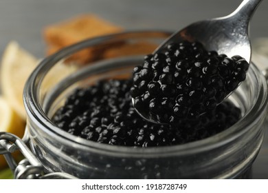 Glass jar and spoon with black caviar, close up