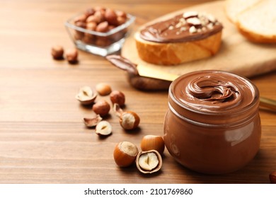 Glass Jar With Tasty Chocolate Hazelnut Spread And Nuts On Wooden Table. Space For Text