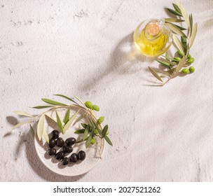 A glass jar with virgin olive oil, textured plate with black olives and a branch of olive tree  - Powered by Shutterstock