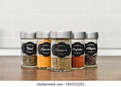 Glass jars with different spices in row on kitchen worktop closeup