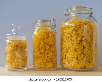 glass jars filled with pasta in different sizes on wood table