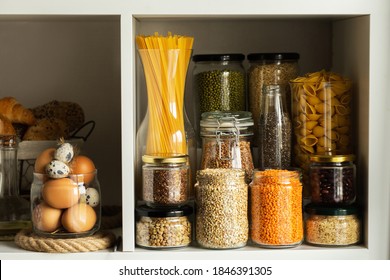 Glass jars with food.Food concept.Shelves in the kitchen.Products on the shelves.Jars of cereals(buckwheat, spaghetti, oatmeal, eggs)in the kitchen shelves.of storage of cereals in the kitchen. - Powered by Shutterstock