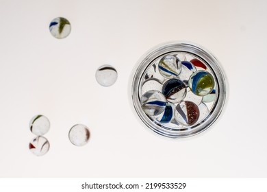 Glass Jars With Marbles Inside Or Falling Into The Jars, White Background