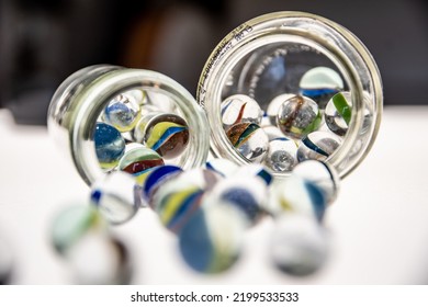 Glass Jars With Marbles Inside Or Falling Into The Jars, White Background