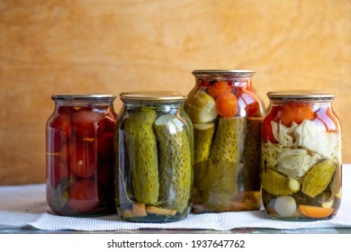 Glass jars with pickled cucumbers (pickles), pickled tomatoes and cabbage. Jars of various pickled vegetables. Canned food in a rustic composition. - Powered by Shutterstock