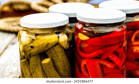 Glass jars with pickled red bell peppers and pickled cucumbers (pickles) isolated. Jars with variety of pickled vegetables. Preserved food concept in a rustic composition. - Powered by Shutterstock