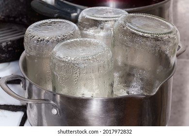 Glass jars in the  stainless steel pot during steam sterilization over the steamer for the home canning - Shutterstock ID 2017972832