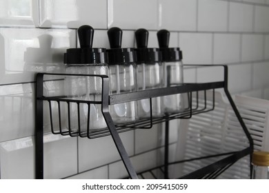 Glass Jars Stand In Row On Black Steel Shelf.