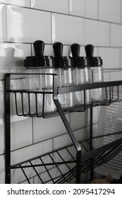 Glass Jars Stand In Row On Black Steel Shelf.