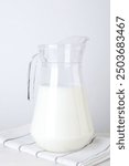 Glass jug of fresh milk on table