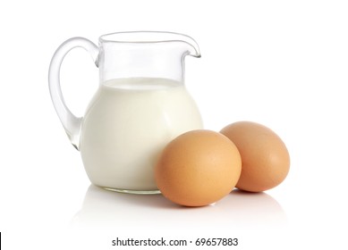 Glass Jug With Milk And Two Eggs On White Background