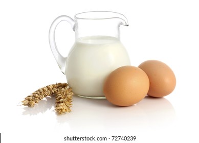 Glass Jug With Milk, Wheat Seeds And Two Eggs On White Background