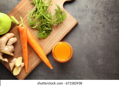 Glass of juice and fresh carrot on cutting board