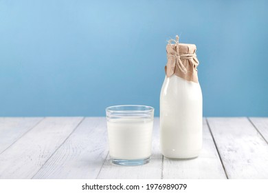 A glass with kefir, homemade yogurt or vegetable milk on a white table and next to a bottle with a drink. Space for text, horizontal photo