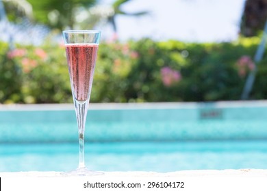 Glass of Kir Royal cocktail on the pool nosing at the tropical resort. Horizontal, cocktail on left side