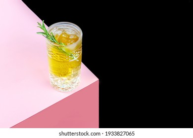 A Glass Of Kombucha Cocktail With Ice And A Sprig Of Rosemary