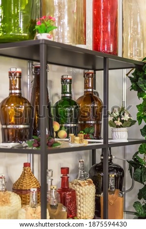 Glass large empty bottles and flasks, for wine and alcoholic beverages on a shelf in a shop window are sold on a shelf