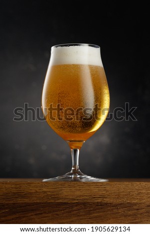 Glass of light beer on dark background. Selective focus