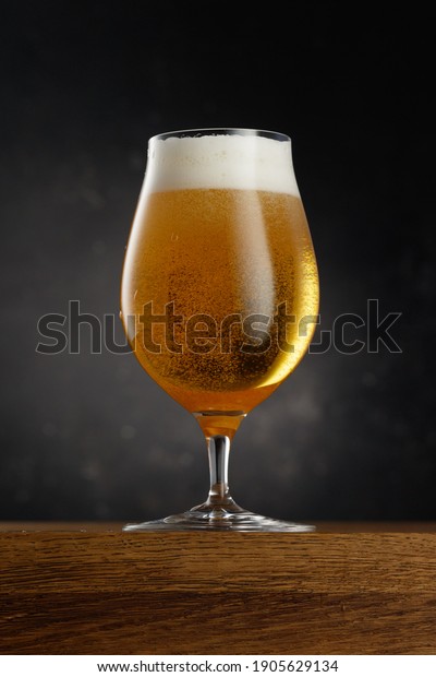 Glass\
of light beer on dark background. Selective\
focus