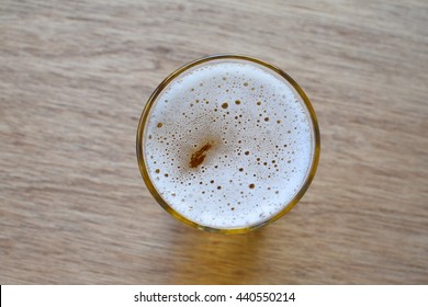 Glass of light beer on wooden background, top view