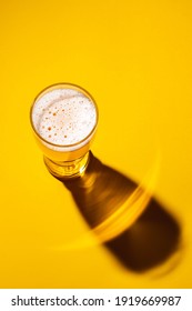 Glass Of Light Beer On A Yellow Background, Top View. Shadow From A Glass Of Lager. 