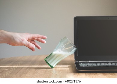 Glass of liquid is about to fall and spill on the keyboard of a laptop. Person trying to reach for the glass. Insurance or warranty concept. Bad luck concept. - Powered by Shutterstock