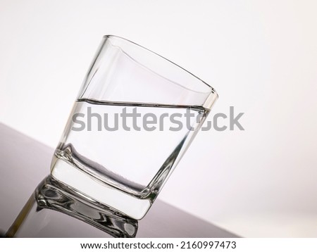 glass for liquor Translucent elements made of glass are placed on a tilted table. empty objects isolated on white background