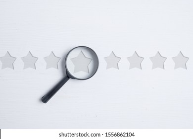 Glass Magnifier Over Abstract Stars On A White Background. Grade Analysis Concept. Best Score. Flat Lay. Close Up.