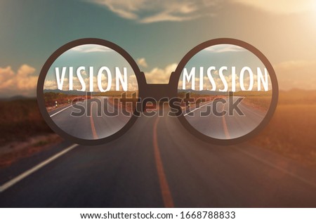 glass magnify against word VISION and MISSION behind the tree of empty asphalt road at golden sunset and beautiful blue sky. Concept for vision.