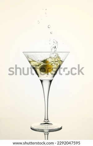 Glass of martini cocktail with olive and splash.