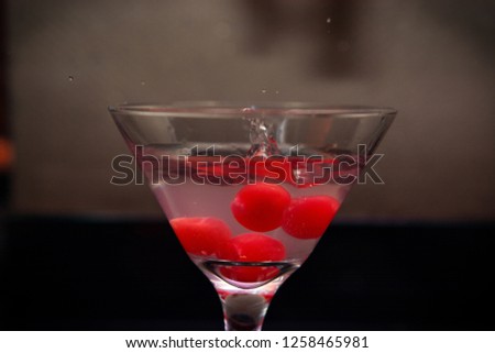 a glass of martini with red cherries 