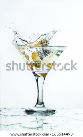 A glass of martini and slice of lemon, a splash and spray on a light background, selective focus