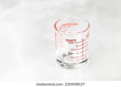 glass measuring cup or dosage cup with ounce measurements displayed.