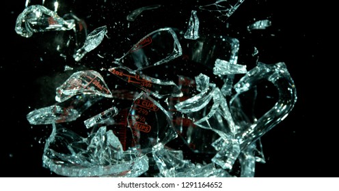 A Glass Measuring Cup Shattering, breaking, exploding into shards on black. Shards everywhere losing form of cup. 