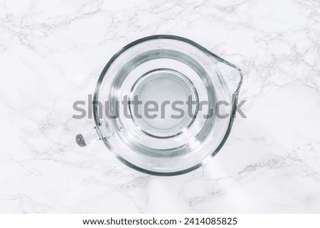 Glass measuring cups are filled with water, lined up and ready to be used in the careful washing of fresh strawberries, ensuring precise and thorough cleaning. Foto stock © 