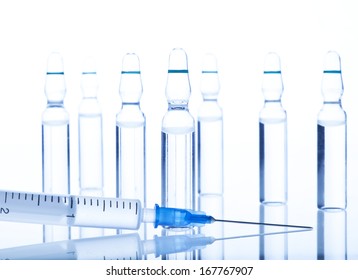 Glass Medicine Ampoules with liquid and botox, hualuronic, collagen and Syringe on a white and blue background.