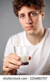 Glass of milk and a handsome guy holding it - Shutterstock ID 2256885707