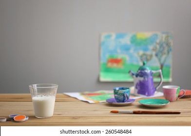 a glass of milk on wood table with paint, brush and paintings - Powered by Shutterstock